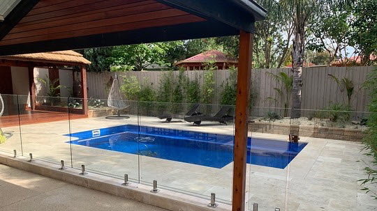 A landscaping project with glass pool fence paving and bali hut